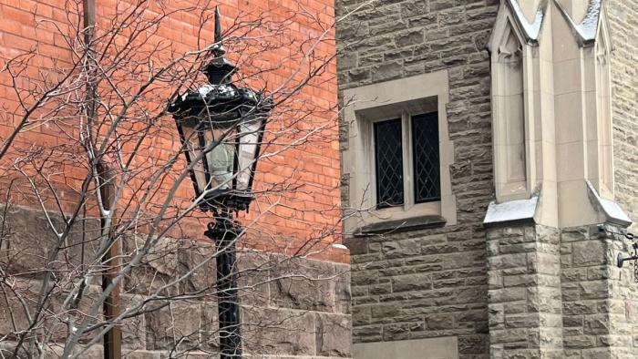 lampstand in winter against WC red brick wall, facing Great Hall