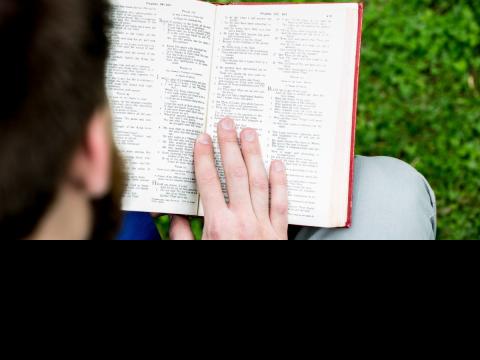 Aidan Armstrong reading Bible on front lawn Principal's Lodge 