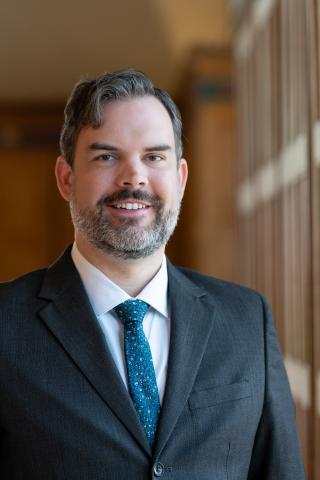 Jeffrey Hocking in Great  Hall against wood panelling (2025)